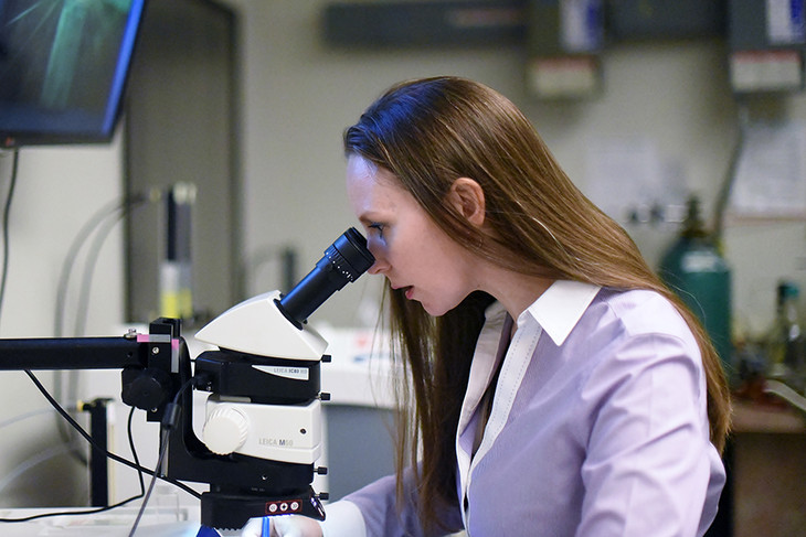 woman looking into microscope